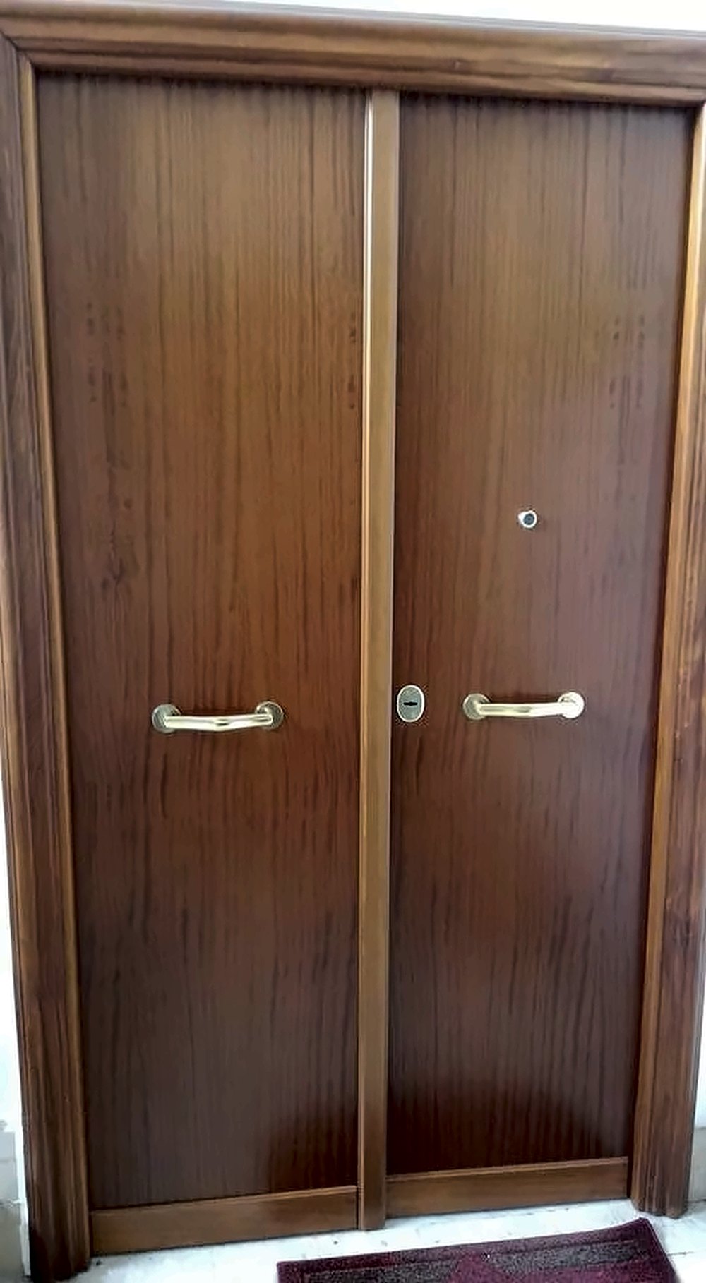 Porta blindata a due ante in legno noce con maniglioni in ottone